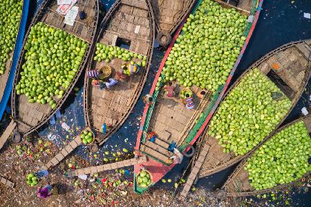 Workers unload watermelons from the boats using big baskets