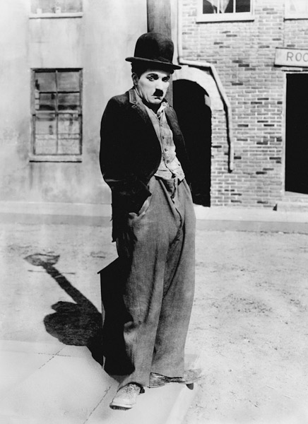 A dog 's life by and with Charlie Chaplin , standing in a street, hands in pockets. Los Angeles van English Photographer, (20th century)