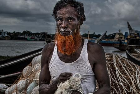 A man from Bangladesh untangling nets.