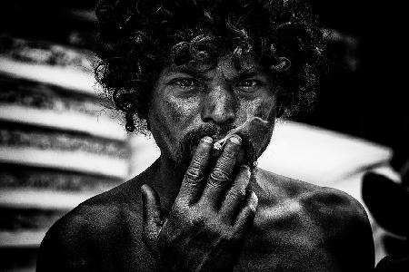 A homeless man smoking in the streets of Delhi.