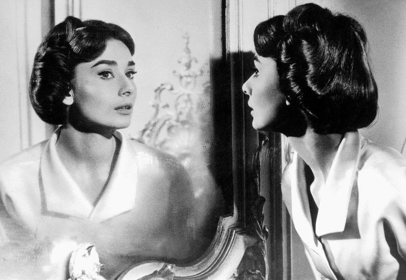 Actress Audrey Hepburn looking at her reflection in the mirror van 
