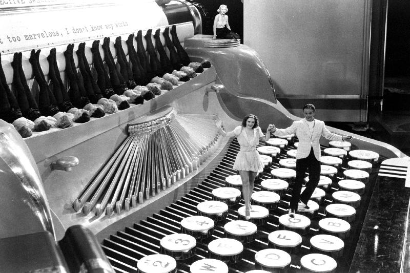 Couple dancing on the key of a giant typewriter, keys are leg of dancers, musical van 