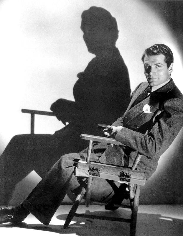English Actor Laurence Olivier seated on a chair's director van 