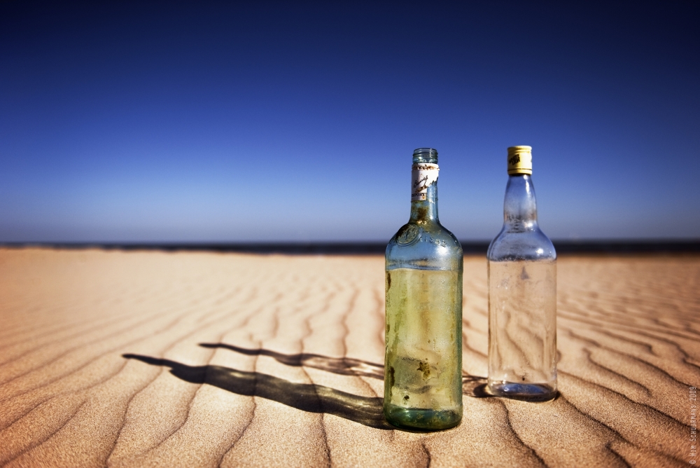 Bottles on sand van Wim Schuurmans